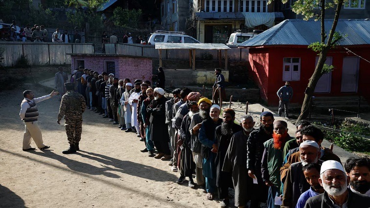 People queue to vote at a polling station in India.